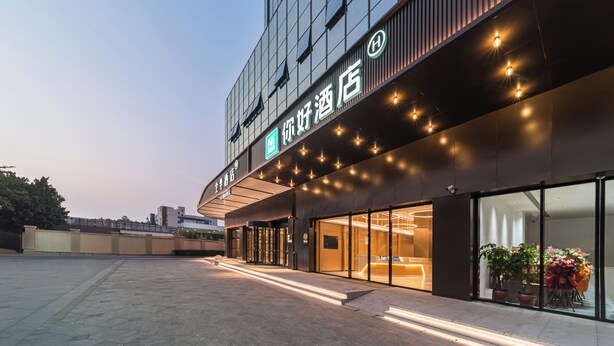A hotel entrance with a modern facade, large glass windows, and outdoor seating area with potted plants. - Ni Hao Hotel Quanzhou Olypmic  Center (Quanzhou)