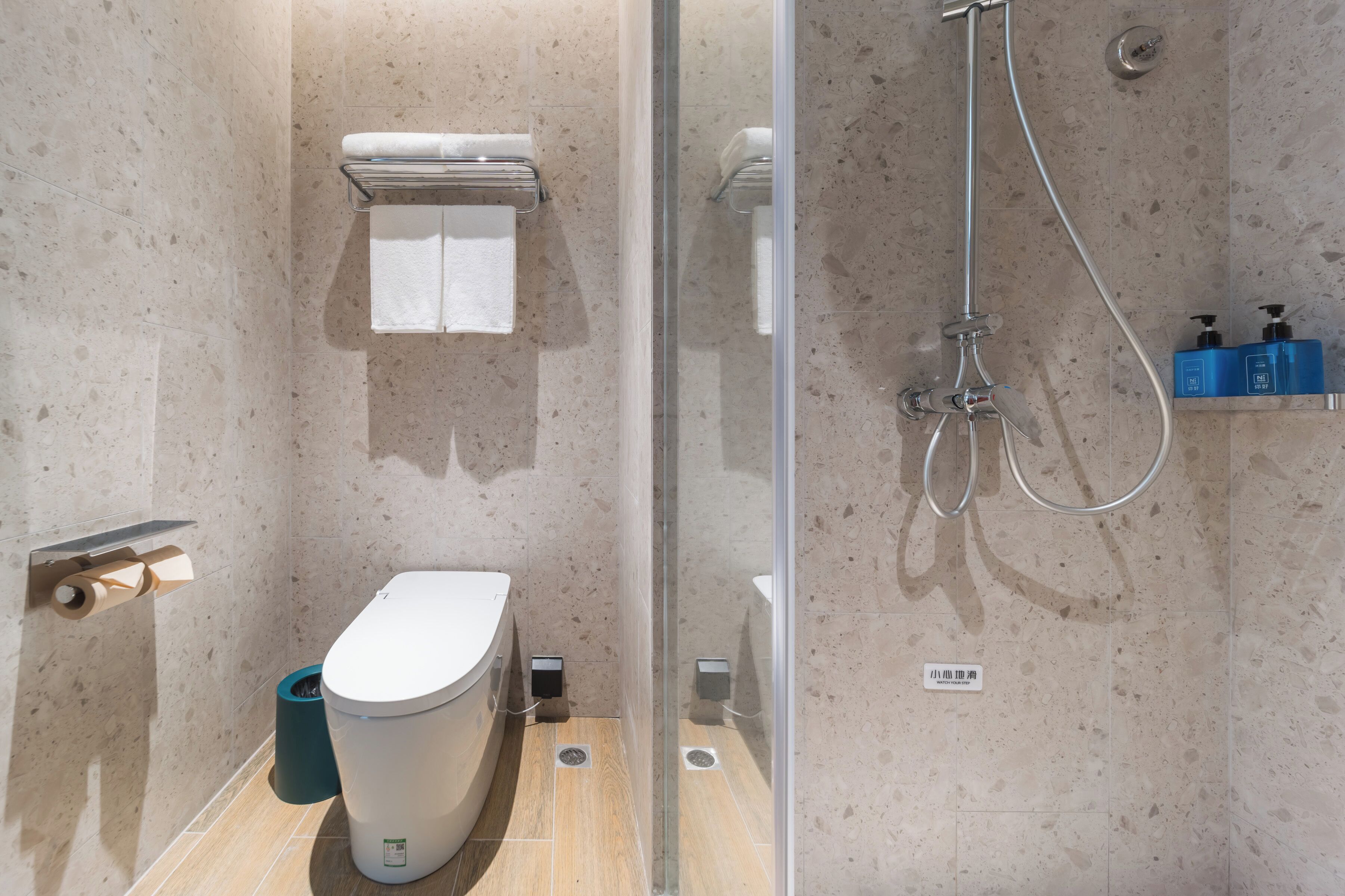 A modern bathroom with a toilet, a glass shower enclosure, and a towel rack.