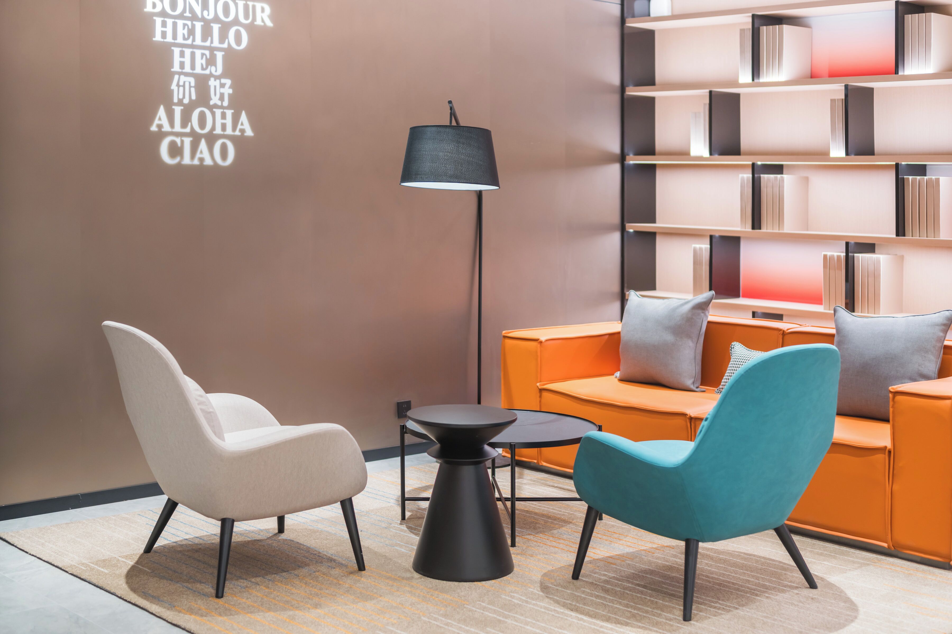 Un espace détente moderne comprenant un canapé, deux fauteuils, une petite table et une bibliothèque.