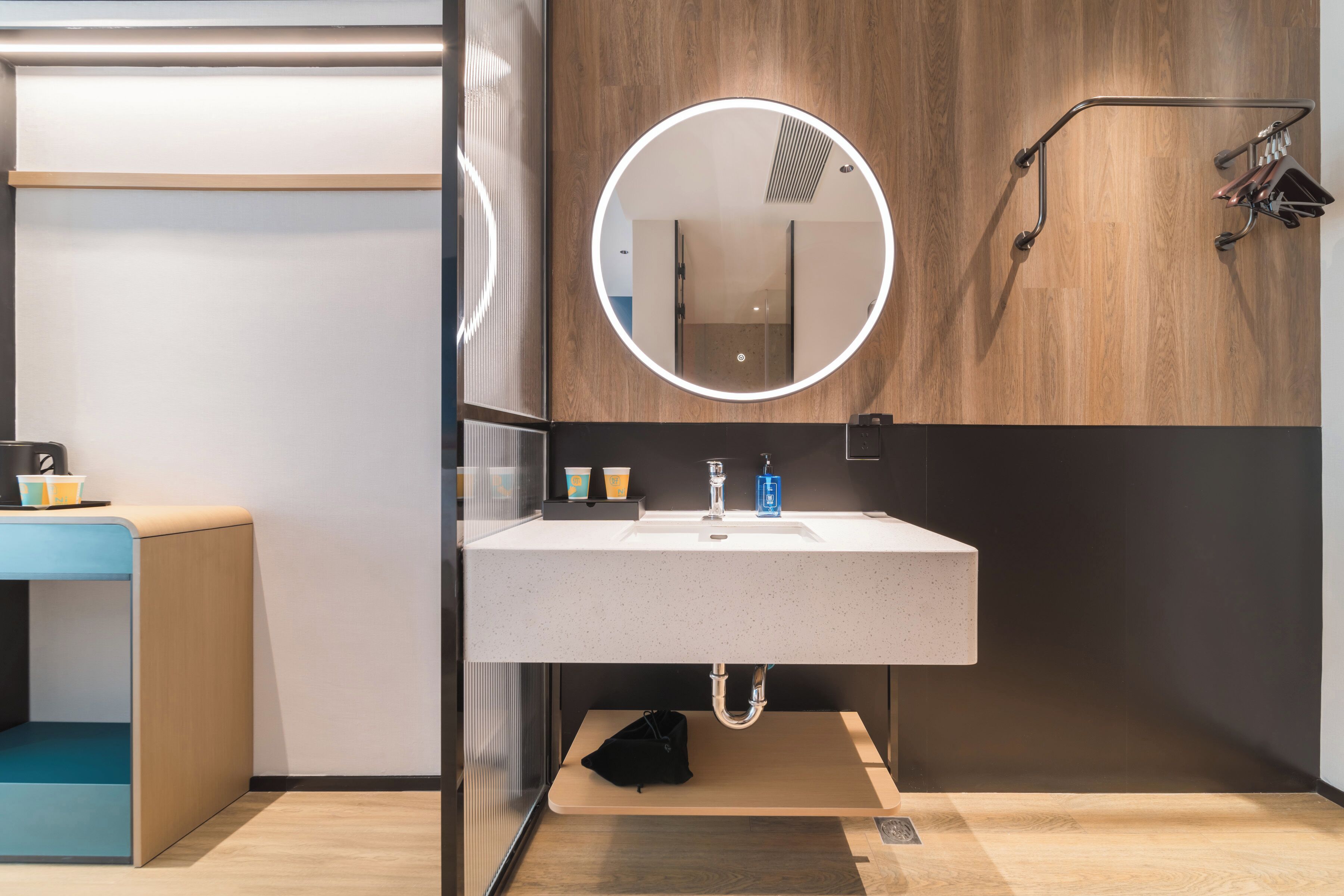 Une salle de bain moderne avec un miroir rond, un lavabo et un porte-serviettes.