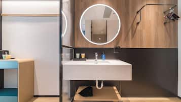 A modern bathroom with a round mirror, a sink, and a towel rack.