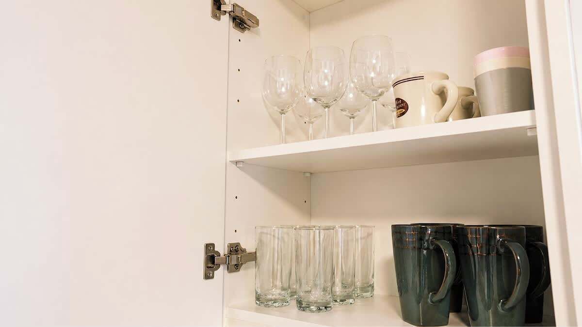 A cabinet with wine glasses and mugs.