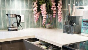 A kitchen with a built-in drawer unit, a coffee maker, and a toaster. - Comfy 3 Beds | 5-min Walk to SkyTrain | 20-min DT (Vancouver)
