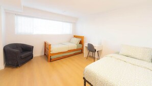 Ein Schlafzimmer mit einem Bett, einem Schreibtisch, einem Sessel und einer Couch.