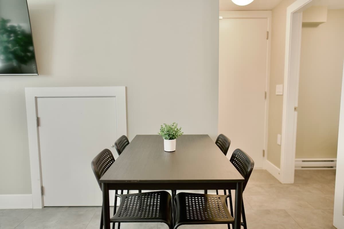 Una mesa de comedor con seis sillas, una planta en maceta y una puerta al fondo.