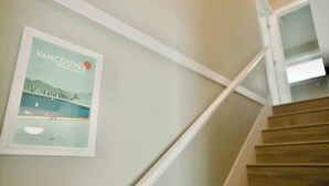 A staircase with wooden steps and white handrails, leading to a landing with a framed picture of Vancouver. - Private 3Bed Entire House/ 15 mins YVR/ 20 mins DT (Vancouver)