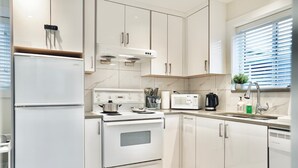 Una cocina moderna con electrodomésticos blancos, estufa, horno, microondas y lavaplatos.