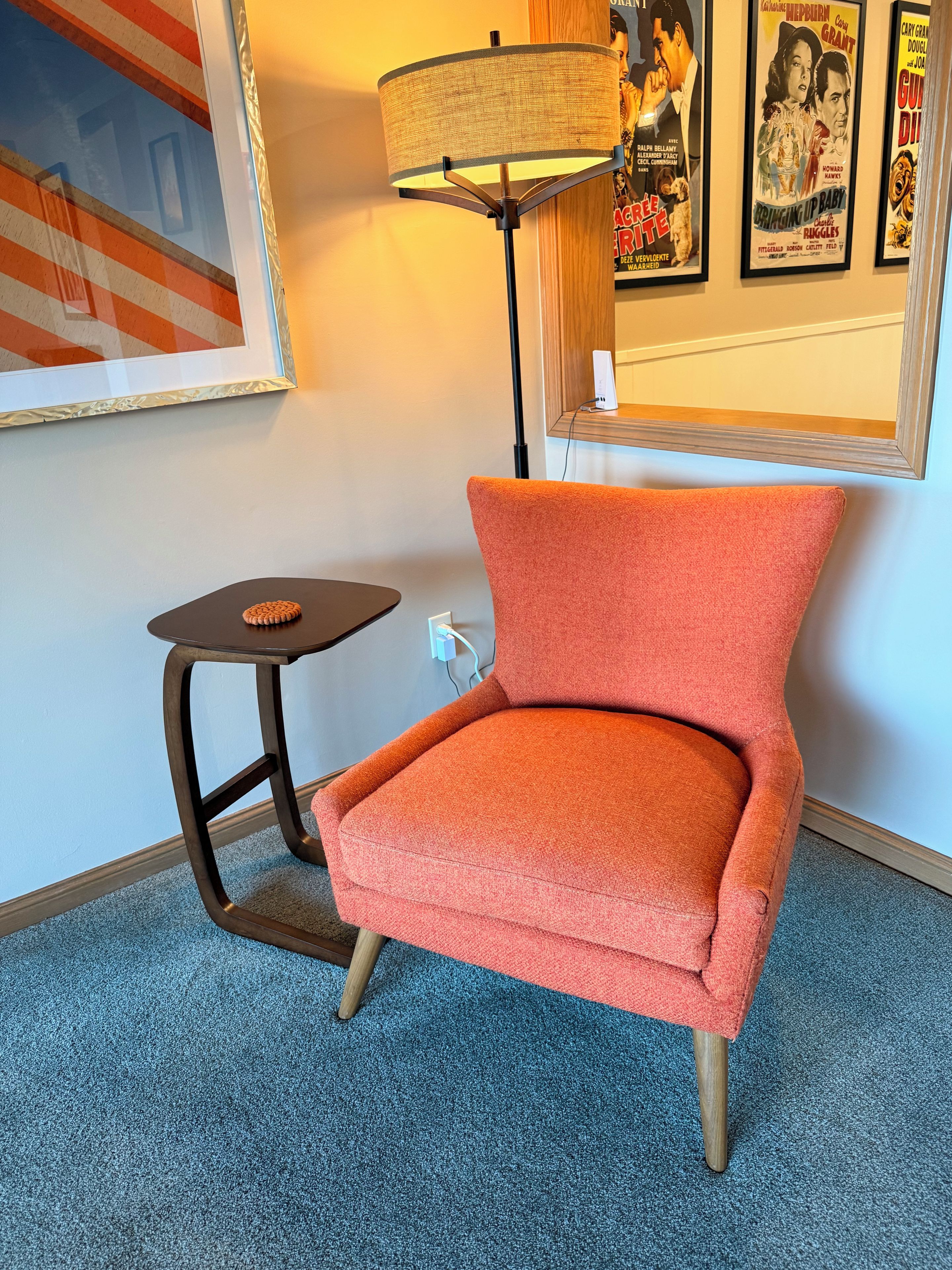 Una habitación con un sillón rojo, una mesita con una galleta y una lámpara.