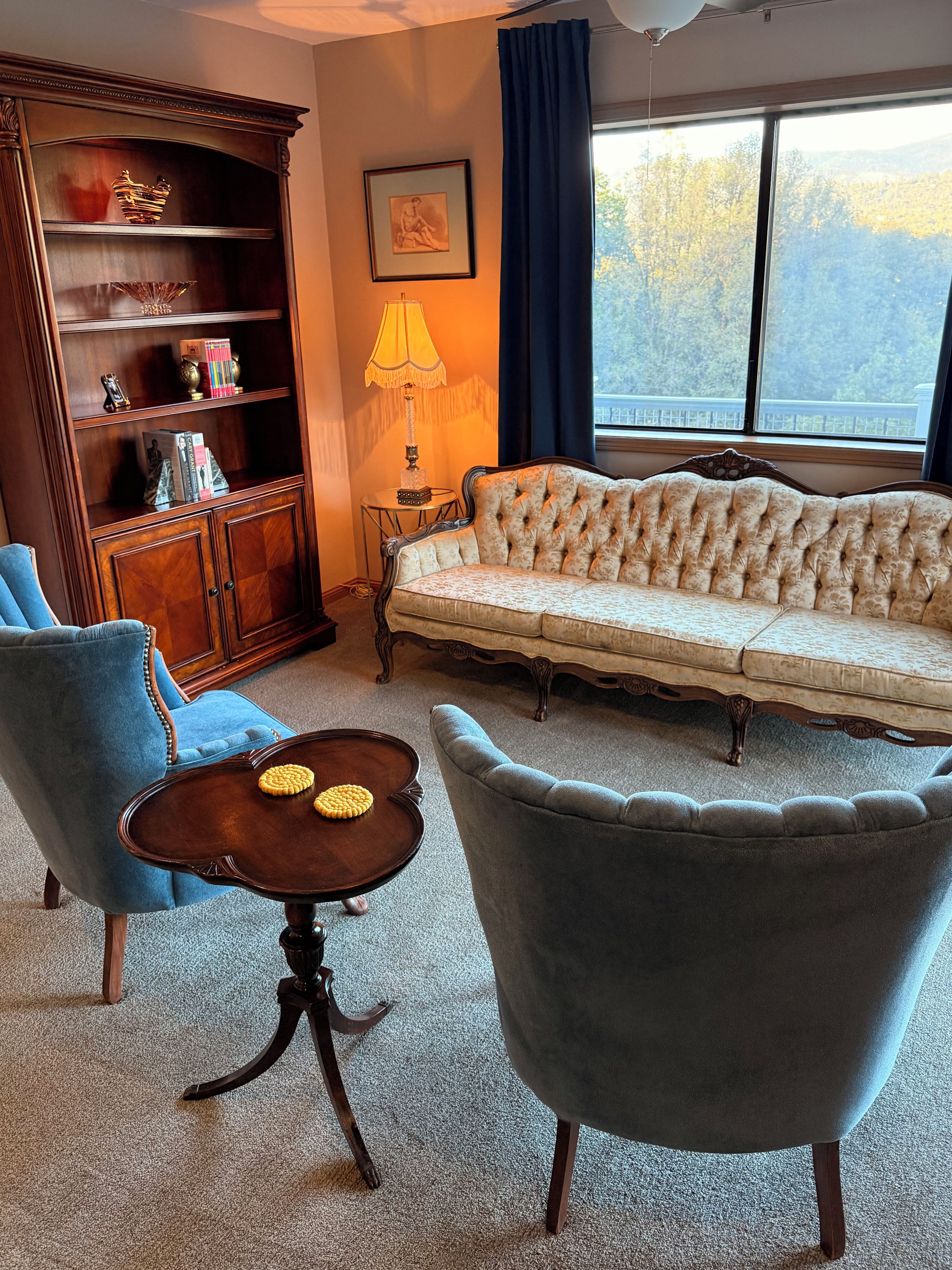 A living room with a sofa, two armchairs, a coffee table, a bookshelf, and a lamp.