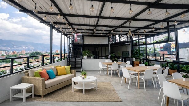 Une terrasse sur le toit aménagée avec un canapé, des chaises, des tables et des plantes en pot.