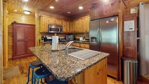 Eine Küche mit Holzausstattung, einem Edelstahlkühlschrank, einer Mikrowelle und einer Arbeitsplatte aus Granit.