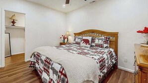 Um quarto com uma cama, um ventilador de teto, uma mesa de cabeceira com abajur e um armário.
