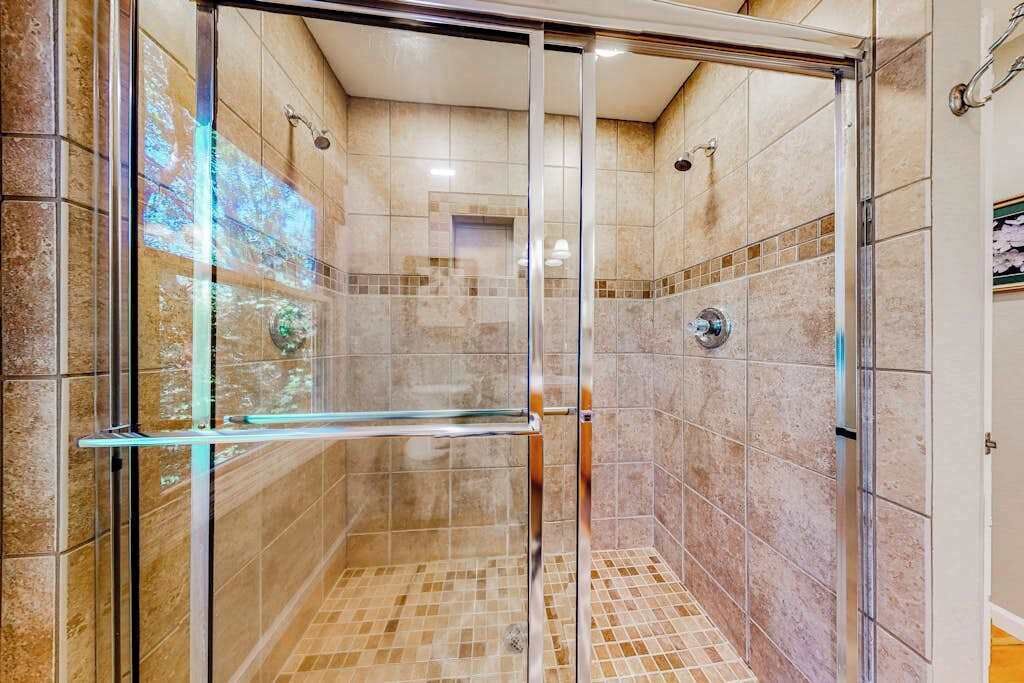 A glass-enclosed shower with tiled walls and a glass door.