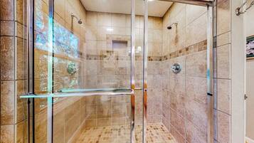 A glass-enclosed shower with tiled walls and a glass door.