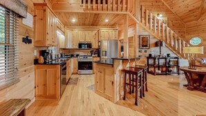 Ein Holzblockhaus-Interieur mit Küche, Essbereich und einer Treppe.