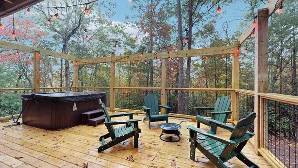 A wooden deck with a hot tub, Adirondack chairs, and a fire pit. - Hawk’s Landing at Innsbruck (Helen)