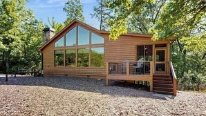 Una cabaña de madera con amplias ventanas, una terraza y una chimenea.