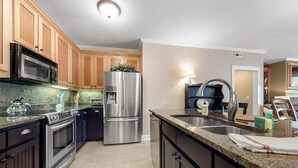 A modern kitchen with stainless steel appliances, wooden cabinets, and a granite countertop. - Lake Chatuge Retreat (Hiawassee)