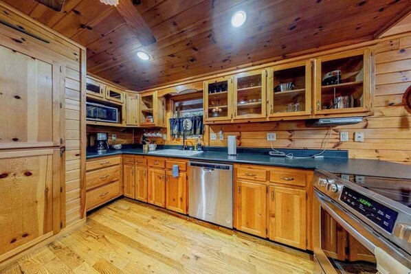 Una cocina de estilo cabaña de madera con armarios empotrados, lavavajillas, microondas y estufa.