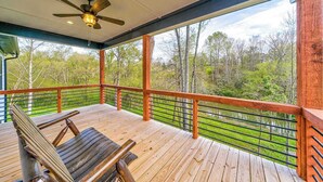 A wooden deck with a ceiling fan, a bench, and a view of a forested area. - Hardwood Hideaway Stay (Ellijay)