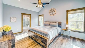 A bedroom with a bed, a ceiling fan, a window, and a bedside table. - Hardwood Hideaway Stay (Ellijay)