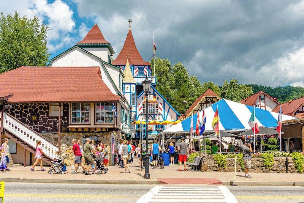 Une place de ville avec un bâtiment imposant, doté d’un toit rouge et d’une tour, entourée d’étals de marché et de passants.