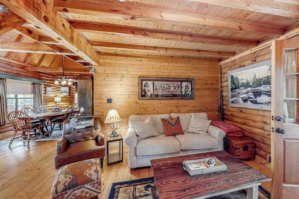 L’intérieur d’une cabane en rondins, avec un coin repas, un canapé et un tableau accroché au mur.