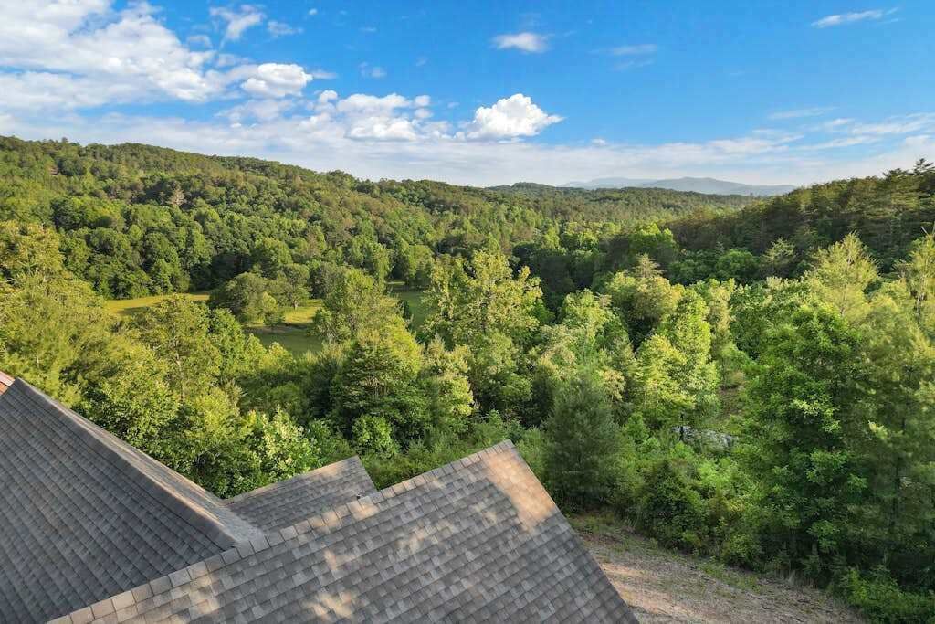 Een uitzicht over een bebost dal, met een huisdak op de voorgrond.