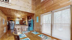 L’intérieur d’un chalet en bois comprend une cuisine, un coin repas et de grandes fenêtres.