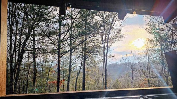 Un bain à remous avec vue sur une forêt et un coucher de soleil.