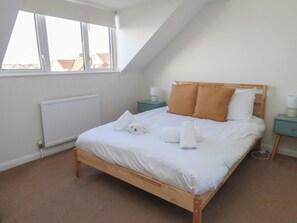Un lit bien fait dans une pièce dotée d’un plafond en pente et d’une fenêtre.