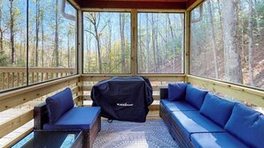 Un espace extérieur aménagé, abrité et doté d’un barbecue, d’une terrasse en bois et d’une vue sur une forêt.