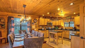 Interior de madera con comedor, cocina y un reloj en la pared.