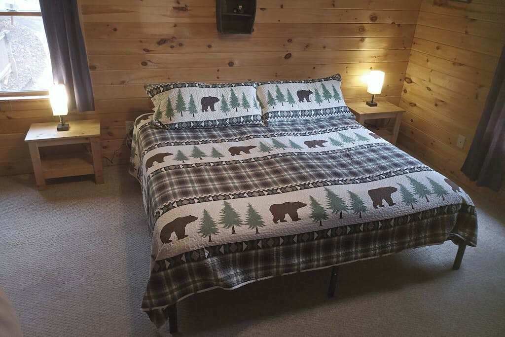 Une chambre dans une cabane en bois, avec un lit, deux tables de chevet et une fenêtre.