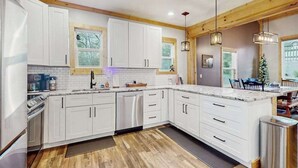 A modern kitchen with white cabinets, a built-in oven, and a large island with a sink. - Maple Summit Ellijay (Ellijay)
