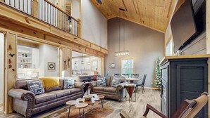 A spacious living room with a high ceiling, a fireplace, and a dining area. - Maple Summit Ellijay (Ellijay)