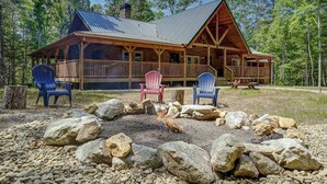 A lodge with a fire pit, outdoor seating, and a large wooden structure surrounded by trees. - The Mountain Chapter (Blairsville)