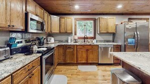 Una cocina con gabinetes de madera, electrodomésticos de acero inoxidable, encimeras de granito y una ventana.