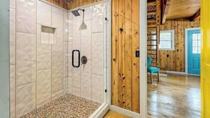 Una stanza con arredamento in legno, una doccia con rivestimento in piastrelle e una porta blu.