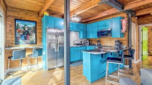 Una cucina con mobili blu, un frigorifero in acciaio inossidabile e un angolo bar con sgabelli.