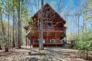 A cabin with a two-story structure, surrounded by trees, and a deck area. - Hid n Timber Getaway (Blue Ridge)