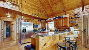 A wooden cabin interior with a kitchen area, a bar counter, and a visible 'GROCERY' sign. - Hid n Timber Getaway (Blue Ridge)