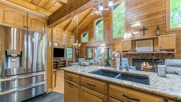 Una cocina con armarios de madera, electrodomésticos de acero inoxidable, encimera de granito y chimenea.