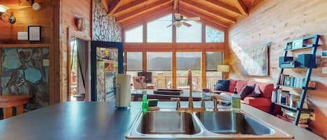 Una cocina con un lavamanos doble, vigas de techo de madera y vistas al exterior.