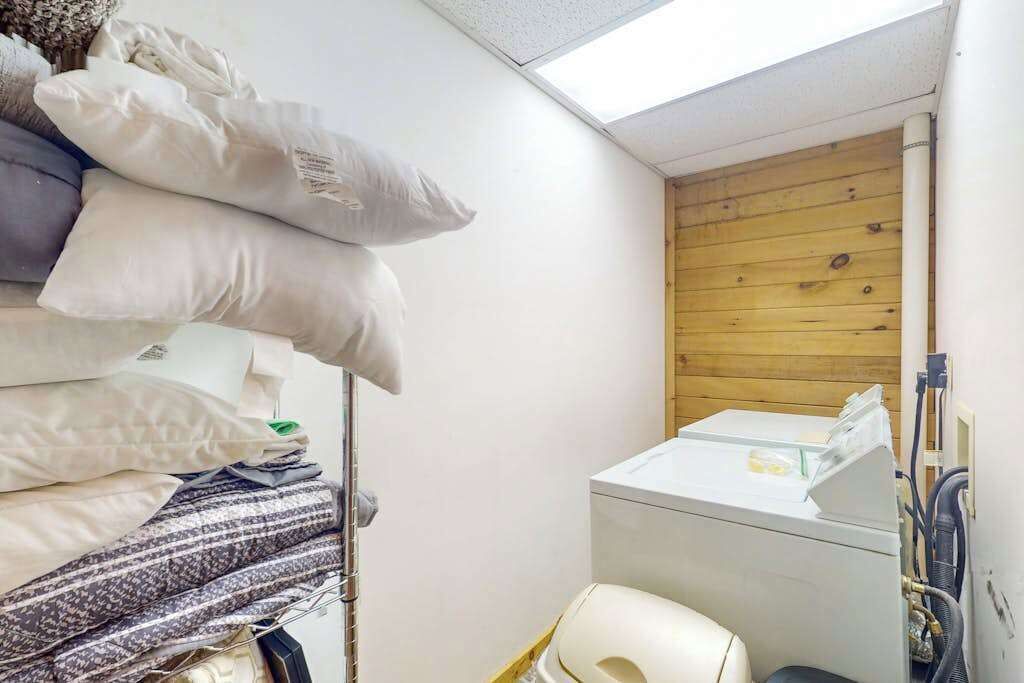 Quarto com cama, máquina de lavar e parede de madeira.