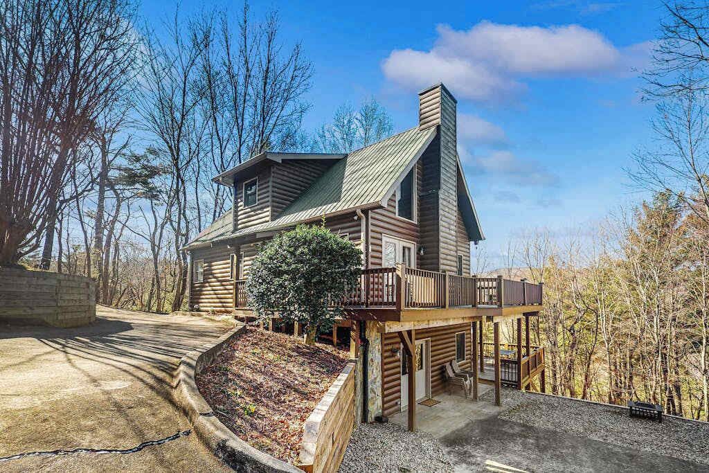 A log cabin with a balcony, a chimney, and a deck.