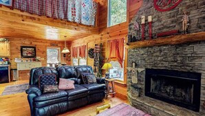 Ein gemütliches Blockhausschlafzimmer mit Kamin, Ledersofa, Holzböden und einer Steinwand.