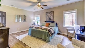 A bedroom with a bed, a ceiling fan, a window, and a desk.