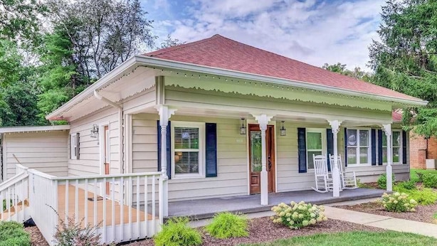 A single-story house with a porch, a front door, and a small deck.