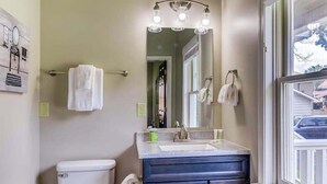A bathroom with a toilet, sink, mirror, and towel rack.